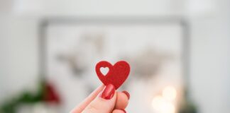 O coração de Deus person holding pink heart ornament