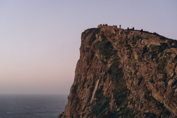 a group of people standing on the edge of a cliff