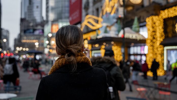 a woman in a black coat is walking down the street