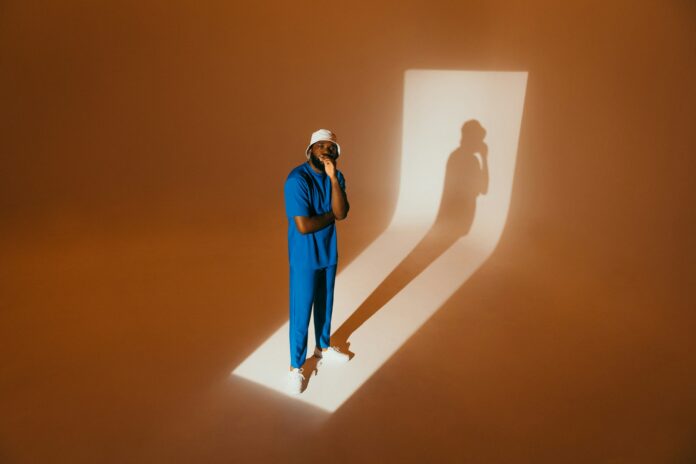 A man contemplates his elongated shadow.