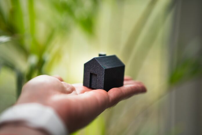 Photo by Jakub Żerdzicki A person holding a small house in their hand