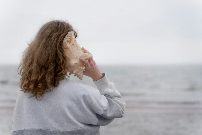 Photo by Anastasiya Badun a woman holding a seashell up to her face