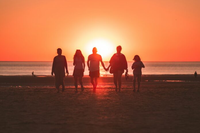 Photo by Kevin Delvecchio silhouette photo of five person walking on seashore during golden hour
