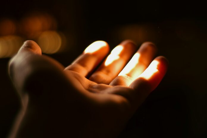 Photo by NADER AYMAN A person holding a lit candle in their hand