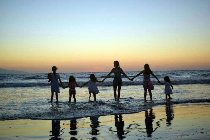Photo by Paola Garcia a family holding hands on the beach at sunset