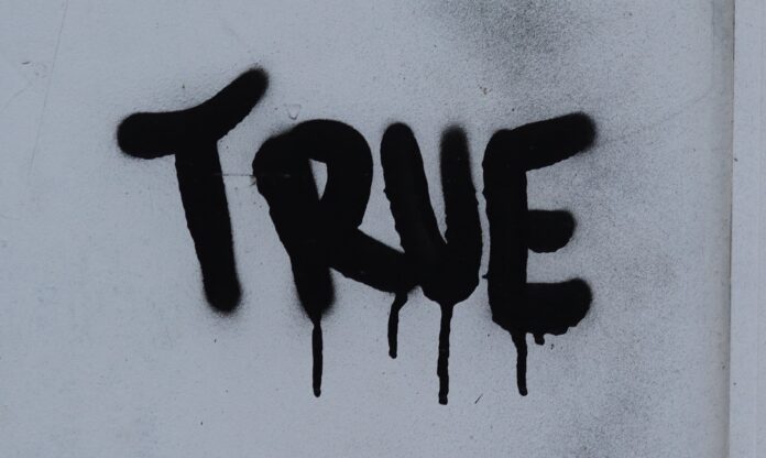 Photo by Jon Tyson the word true is spray painted on a white wall