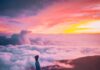 Reflita sobre o poder man sitting on mountain cliff facing white clouds rising one hand at golden hour