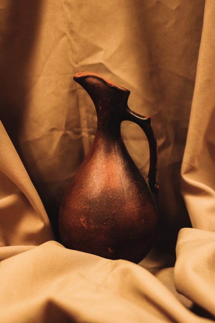 Earthenware jug with handle on draped fabric