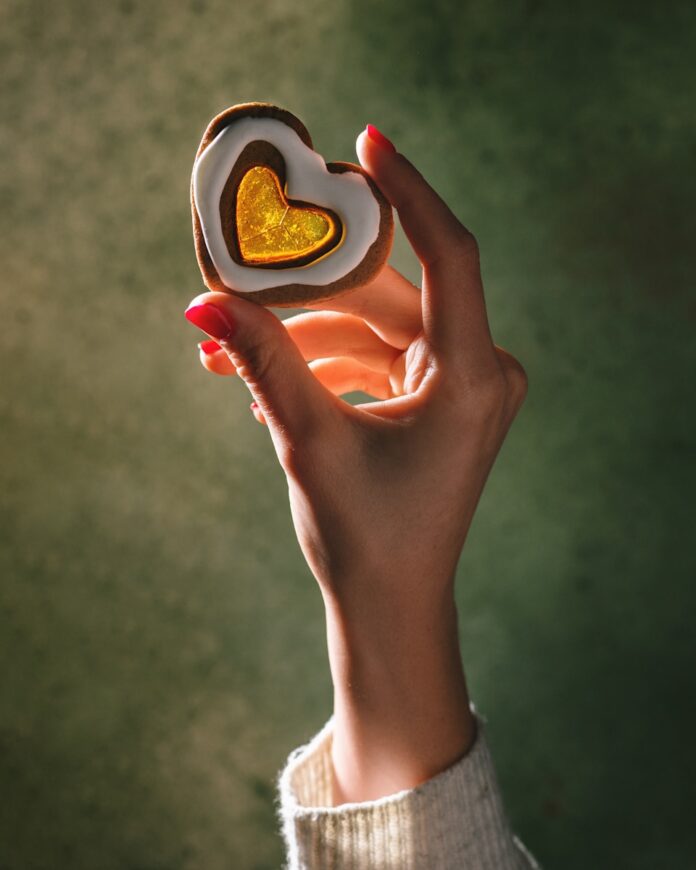Photo by Julia Vivcharyk A person holding a heart shaped cookie in their hand