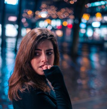 Entregue seu medo a Deus a woman standing on a sidewalk in the rain