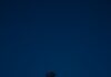 Um passo suficiente Person holding a lit lantern against a dark blue sky