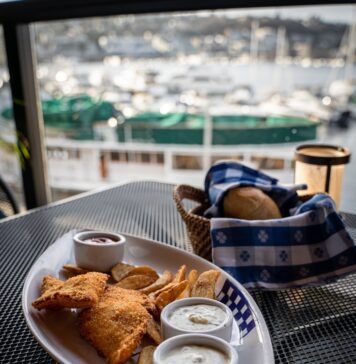 Pães, peixes e Jesus a plate of food on a table with a view of a harbor