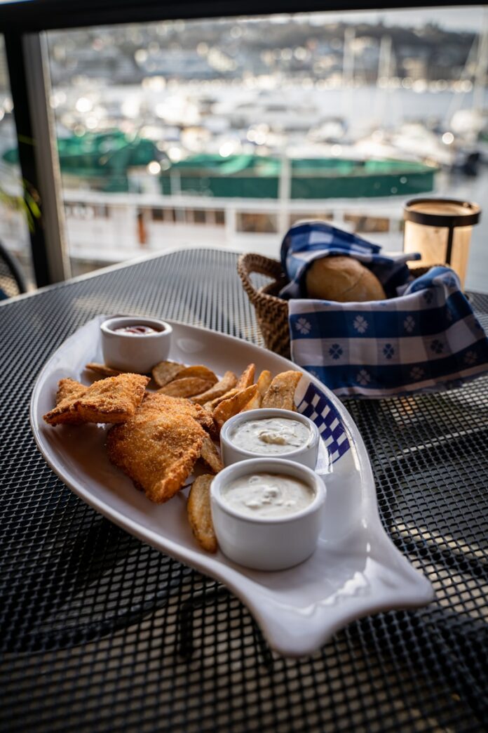 Photo by Alexandra Tran a plate of food on a table with a view of a harbor