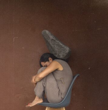 Bagagem espiritual Woman curled on chair with rock overhead