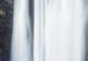 Somente crer person standing beside waterfall