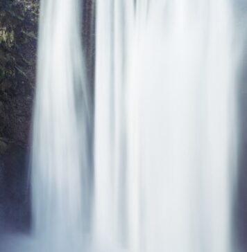 Somente crer person standing beside waterfall