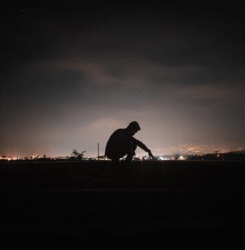 Perto e ativo a man sitting on a bench in the dark