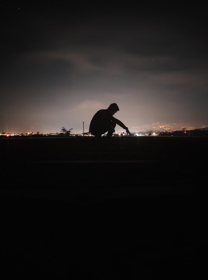 a man sitting on a bench in the dark