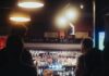 Outros estão observando a group of people standing around a bar