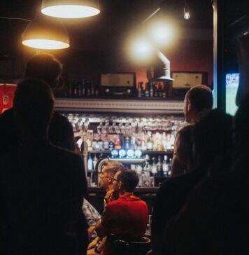 Outros estão observando a group of people standing around a bar