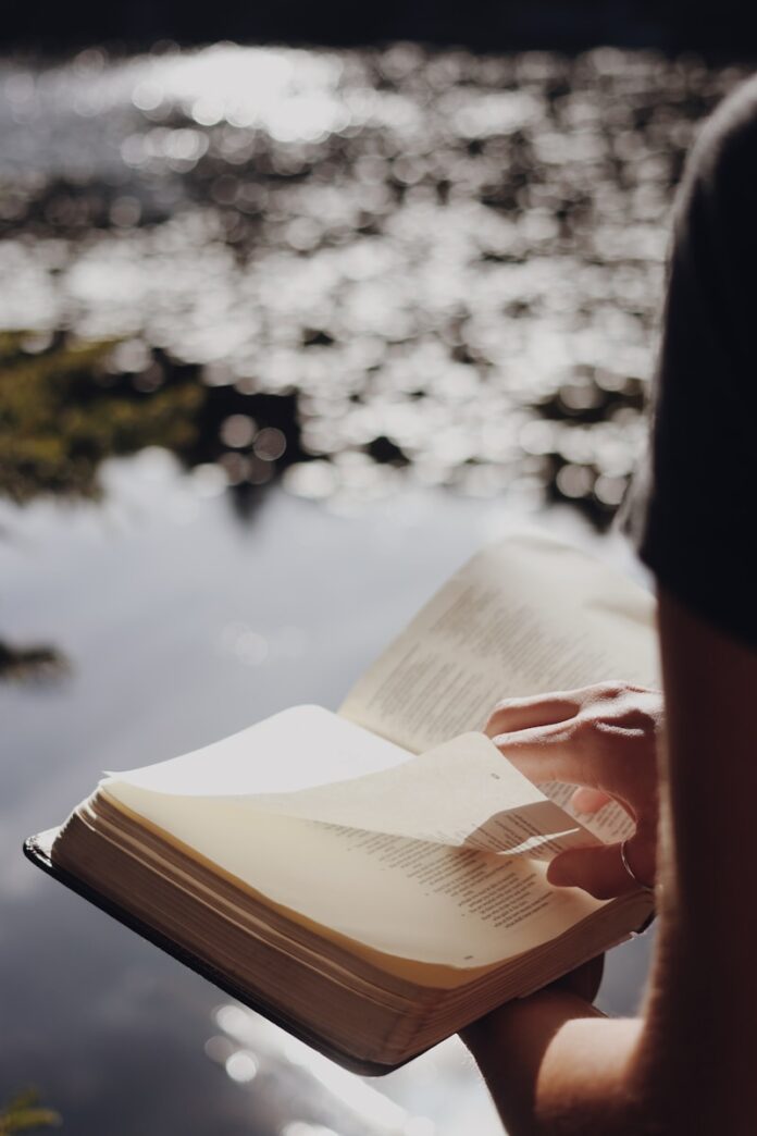 Photo by Jessica Mangano person in black long sleeve shirt holding book