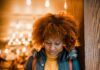 A escolha é nossa woman in brown leather jacket standing beside brown wooden wall
