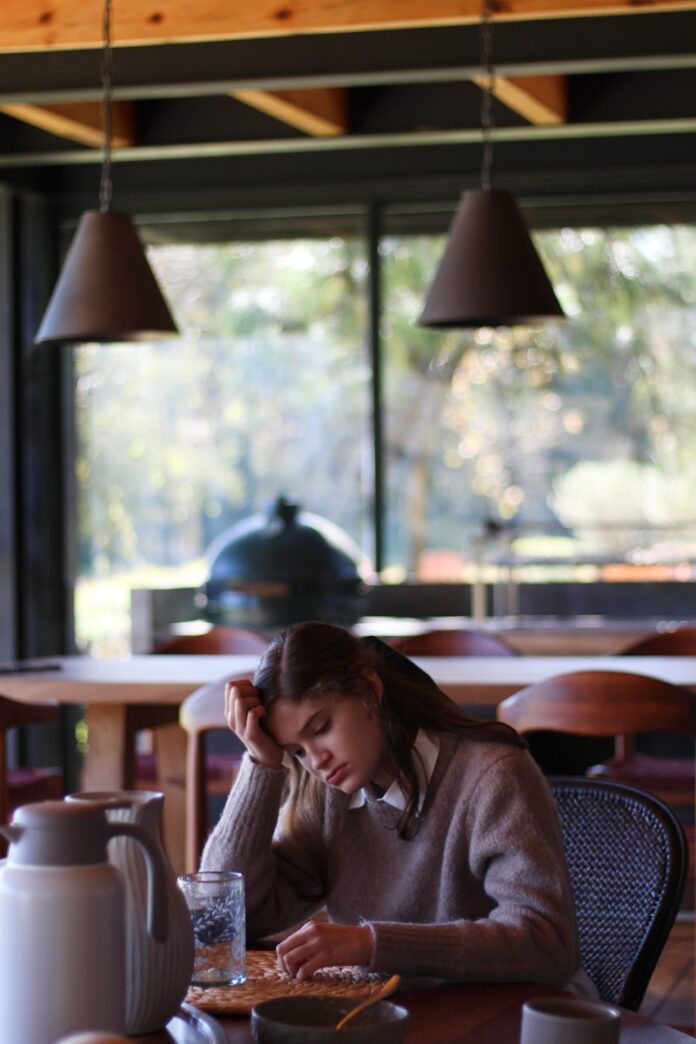 Photo by Lucia Macedo woman in gray long sleeve shirt sitting on brown wooden chair