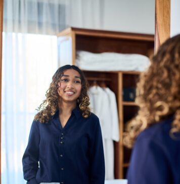 O valor de uma boa escolha Woman in navy shirt and white pants smiles at mirror