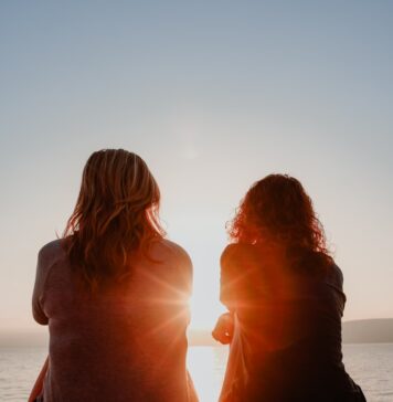 Uma presença garantida two woman sitting on beach sand while facing sunlight