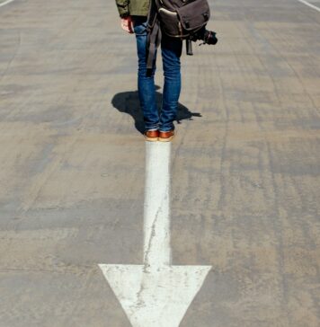 Superando o passado person standing on arrow sign on road