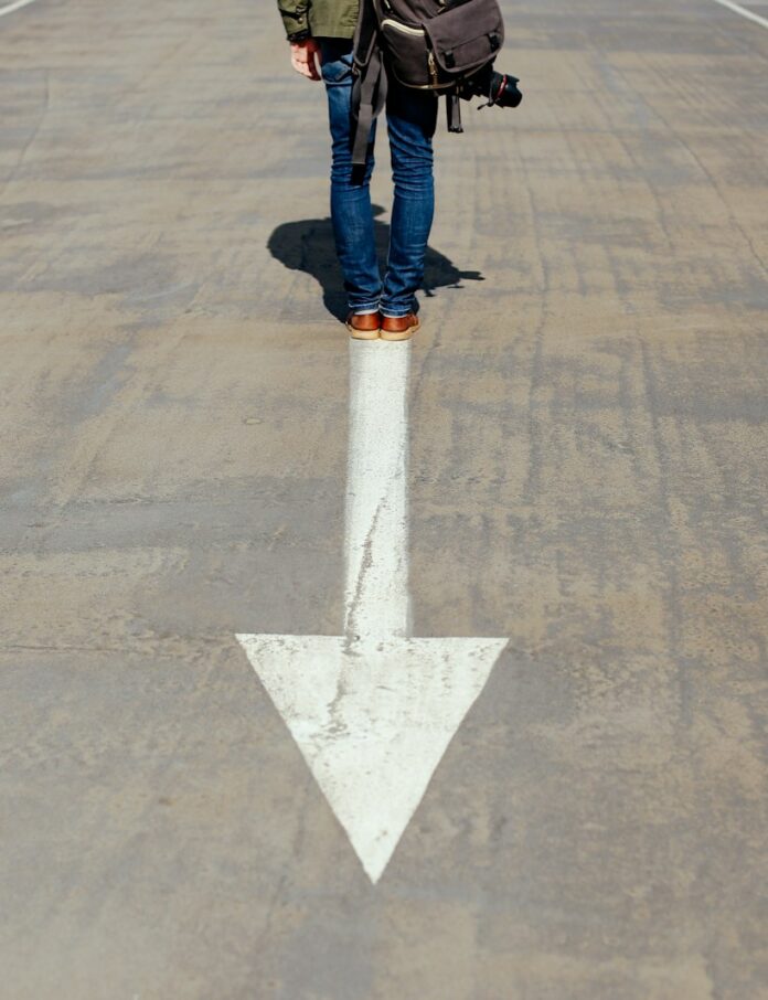 Photo by Smart person standing on arrow sign on road
