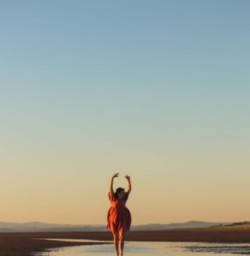 Graça reconfigura seu coração a woman in a red dress is running on the beach