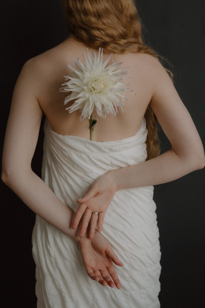 Photo by Alina Bondar Woman with white flower on her back