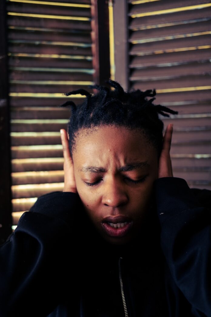 Photo by Adelade Mbuyazi a woman with dreadlocks covering her ears