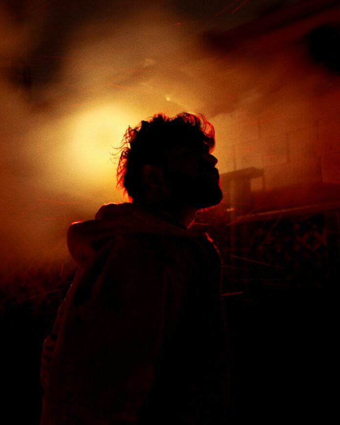 Photo by eldhose kuriyan Man silhouetted against a bright orange light