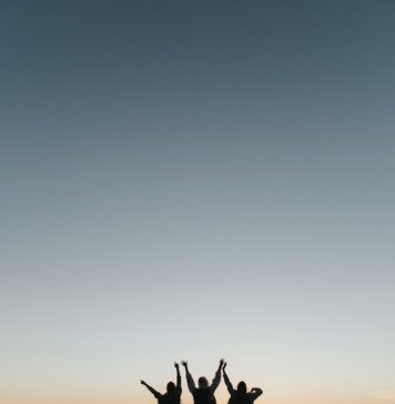 O que Jesus celebra silhouette photography of persons raising hands while standing on island