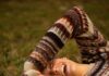 Uma vida de alegria e abundância woman in brown and white sweater lying on green grass field during daytime