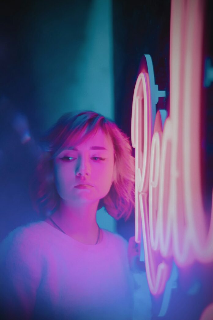 Photo by Den Trushtin woman standing beside neon light