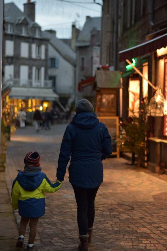 Photo by Renaud Confavreux a woman and a child walking down a street