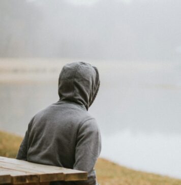 Sentar em silêncio person in gray hoodie sitting on picnic table staring at the fog during daytime